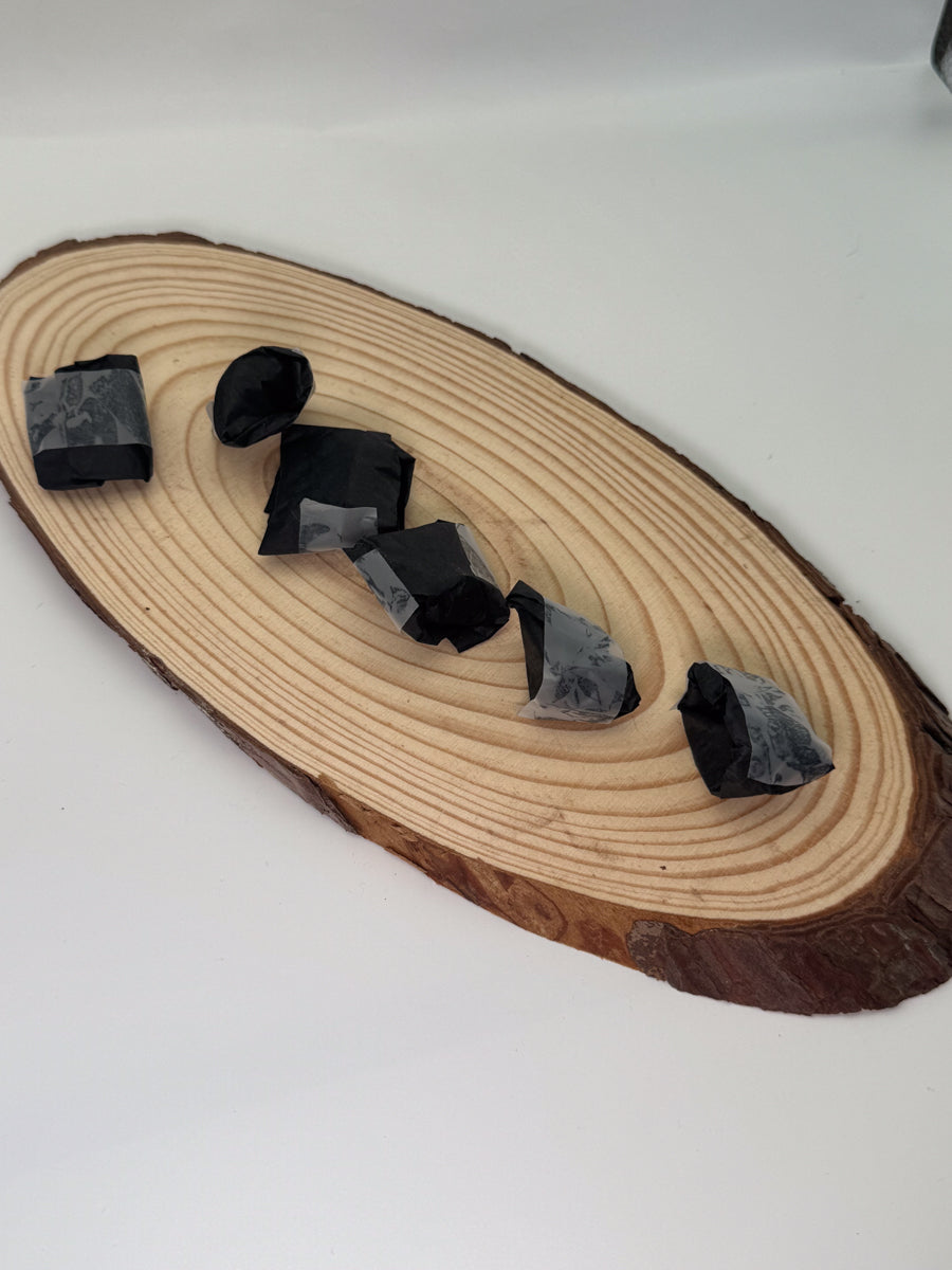 Wooden slice with black mystery crystals on a white background