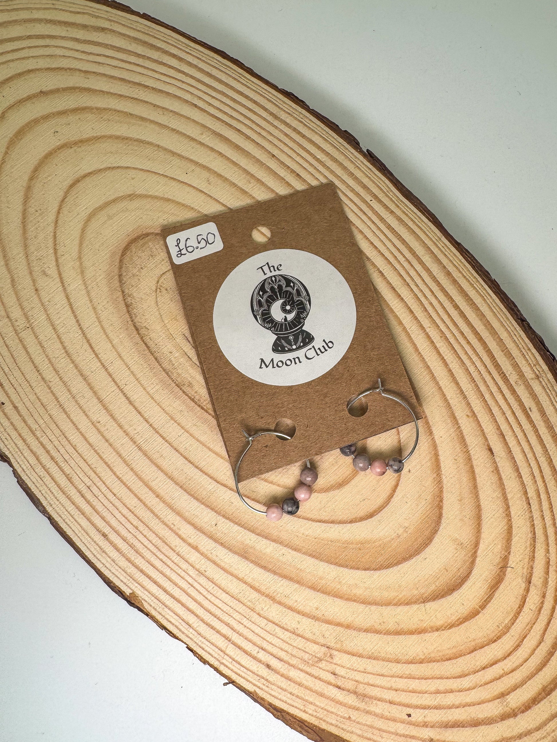 Earring card with rhodonite earrings on a wooden surface