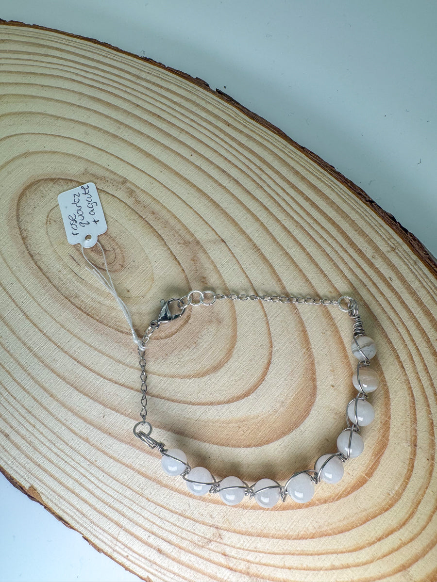 Silver bracelet with rose quartz beads on a wooden surface