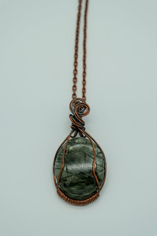 Necklace with a green stone pendant on a light gray background