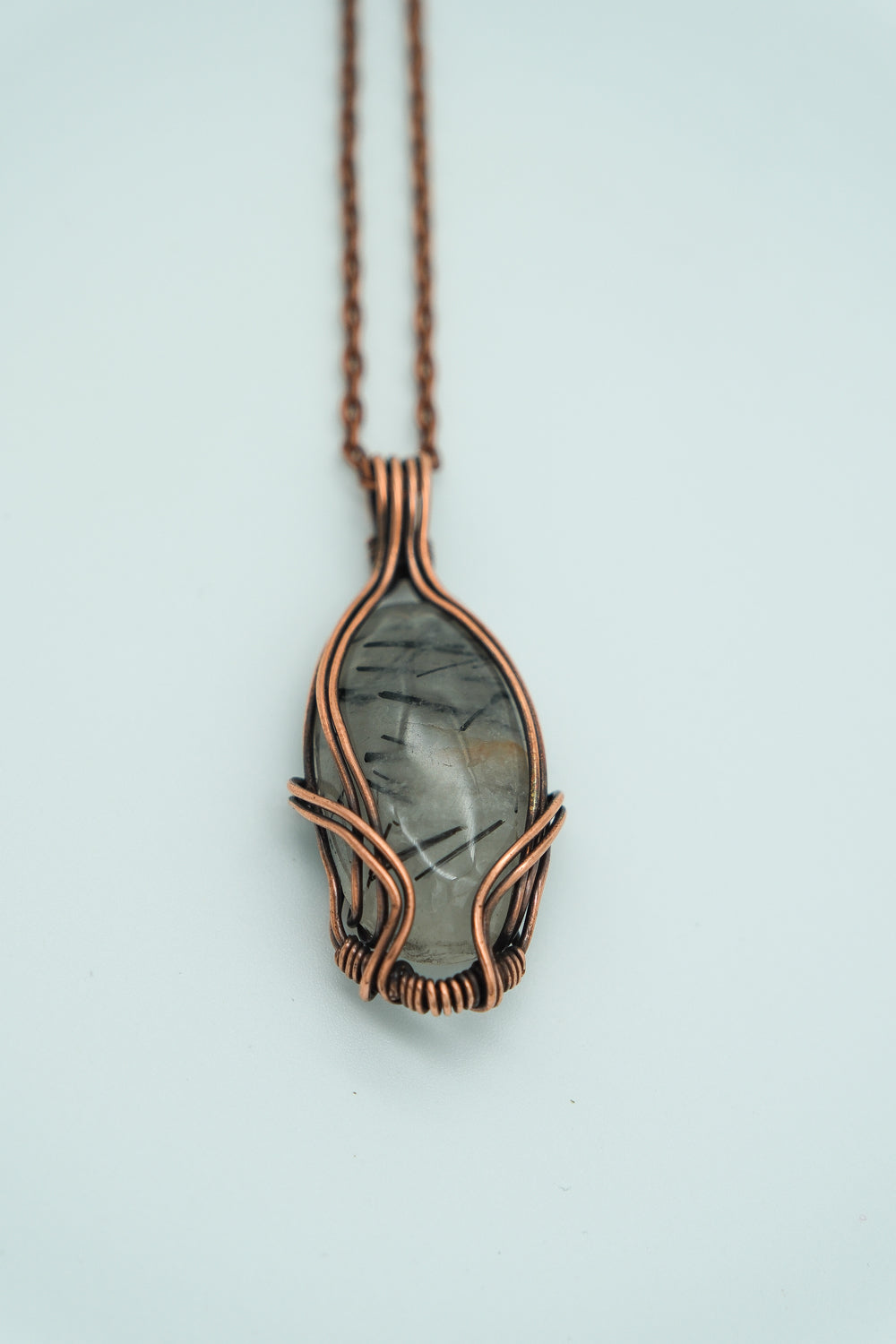 Necklace with a copper-wrapped pendant on a light blue background