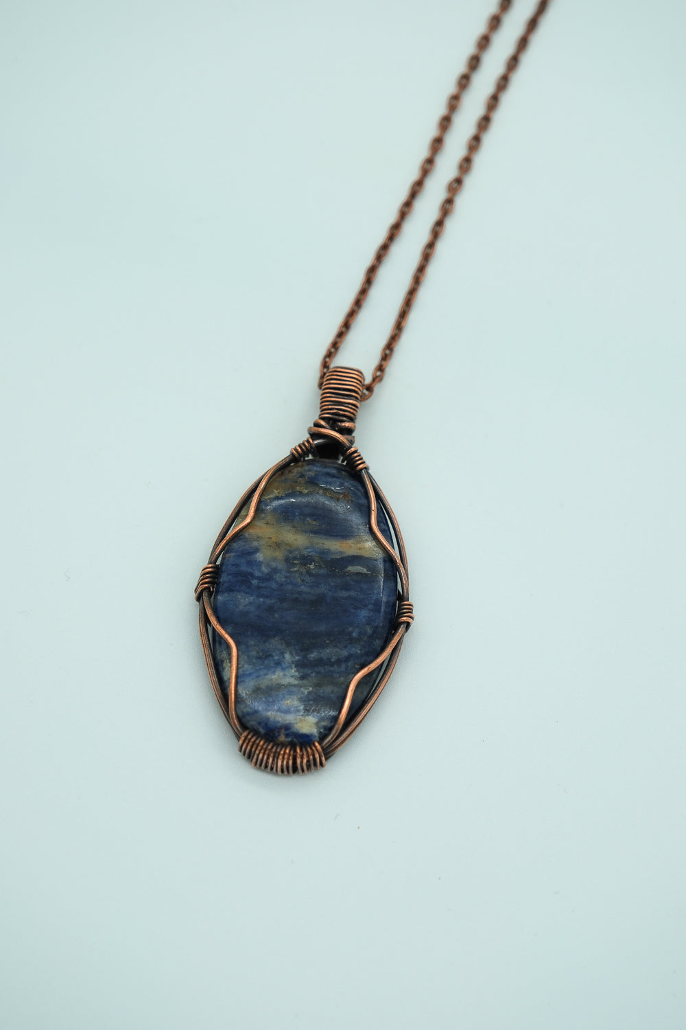 Necklace with a blue stone pendant on a light blue background